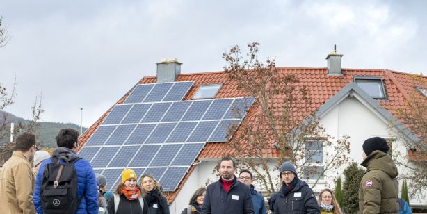 Menschengruppe von Haus mit Dachflächen-PV 